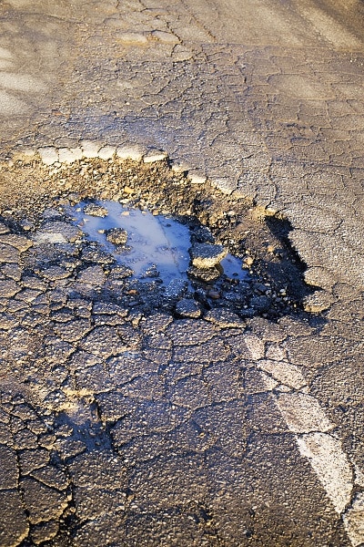 Road damage - Pot Hole - HMA Contracting Featured Image for Potholes Can Damage Vehicles and Your Business Reputation